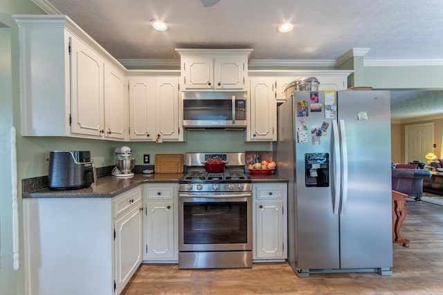 kitchen featuring crown molding, light wood-type flooring, white cabinets, and appliances with stainless steel finishes