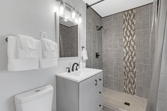 bathroom featuring a tile shower, vanity, and toilet