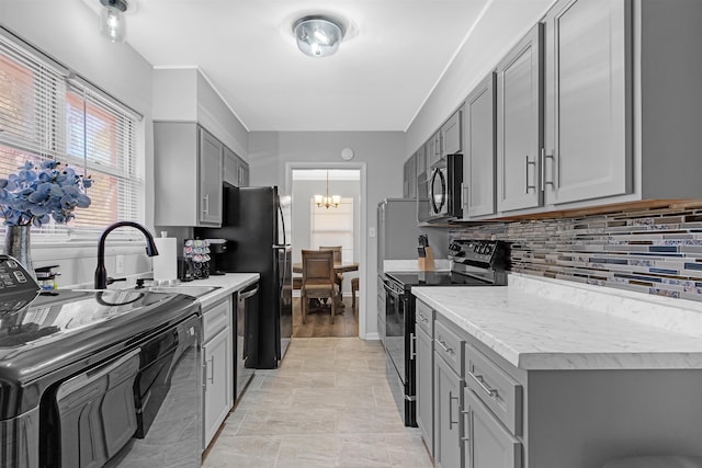 kitchen with black range with electric stovetop, a notable chandelier, gray cabinets, and stainless steel dishwasher