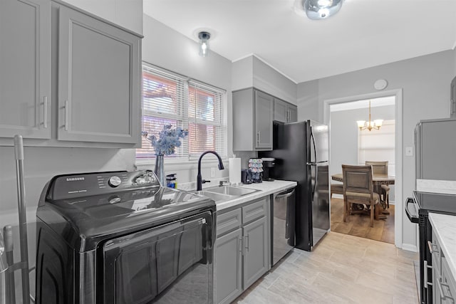 kitchen featuring sink, gray cabinets, black appliances, washer / clothes dryer, and a chandelier