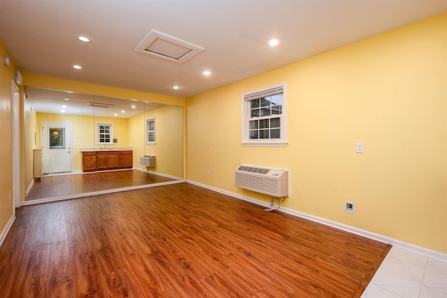 unfurnished living room with a wall mounted air conditioner and light hardwood / wood-style flooring