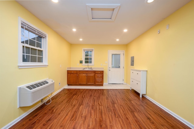 interior space featuring a wall mounted air conditioner, sink, and light wood-type flooring