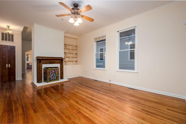 unfurnished living room featuring ceiling fan, hardwood / wood-style floors, a multi sided fireplace, ornamental molding, and built in shelves