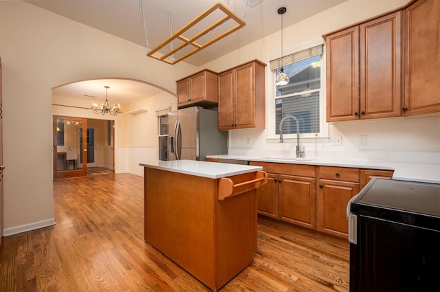 kitchen featuring sink, stainless steel fridge, hanging light fixtures, electric range oven, and a kitchen island