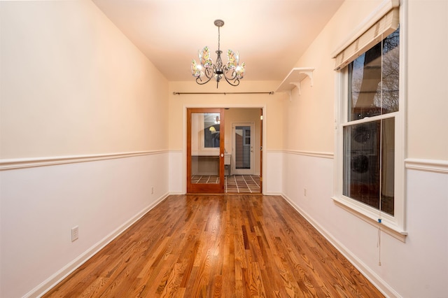 unfurnished room featuring wood-type flooring and a notable chandelier