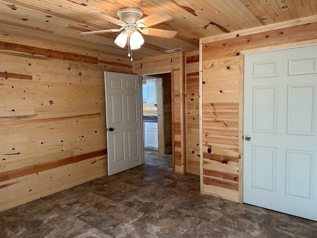 empty room with ceiling fan, wood ceiling, and wooden walls