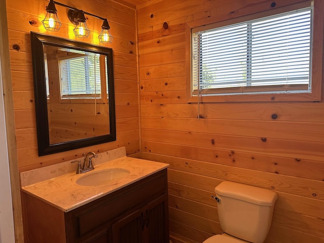 bathroom featuring vanity, wooden walls, and toilet