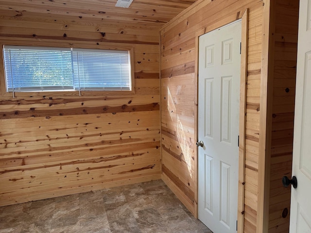 unfurnished room with wood ceiling and wooden walls