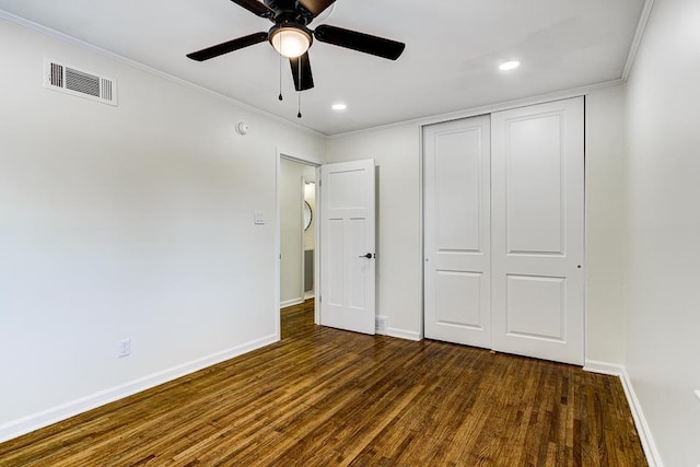 unfurnished bedroom with dark hardwood / wood-style flooring, ornamental molding, and a closet