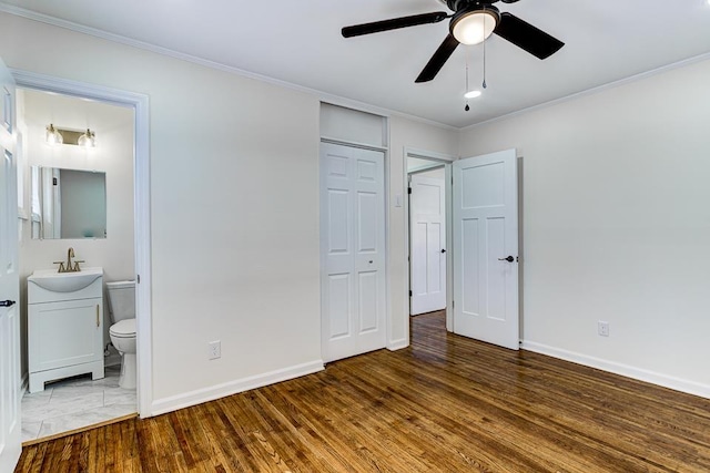 unfurnished bedroom with sink, crown molding, and wood-type flooring