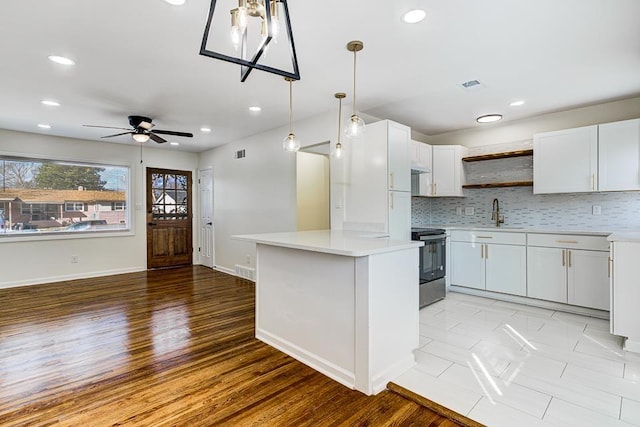 kitchen featuring pendant lighting, sink, stainless steel electric range, tasteful backsplash, and white cabinets