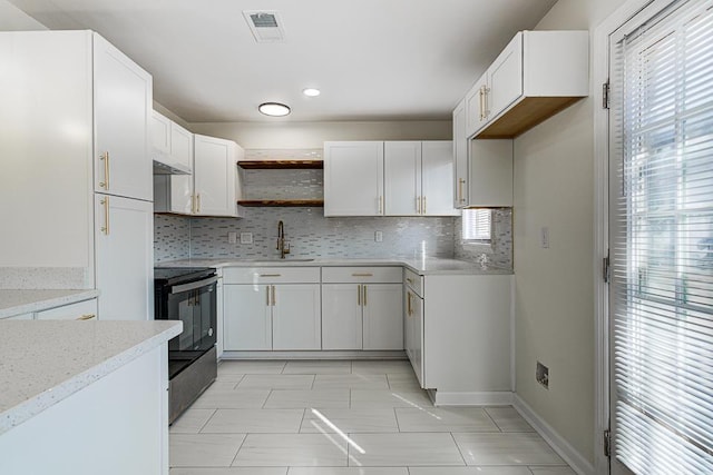 kitchen featuring white cabinetry, black electric range oven, light stone countertops, and sink