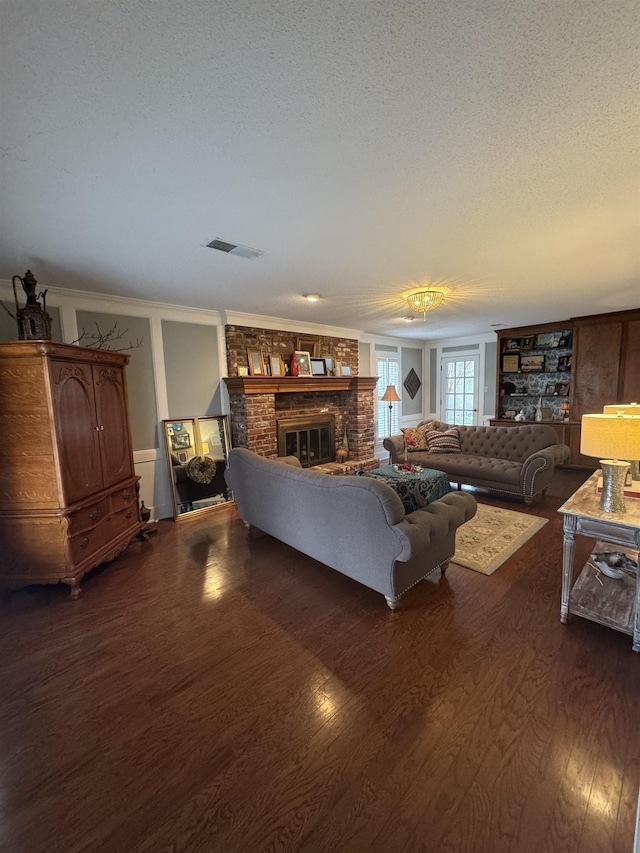 living room featuring a brick fireplace, dark wood-type flooring, and a textured ceiling