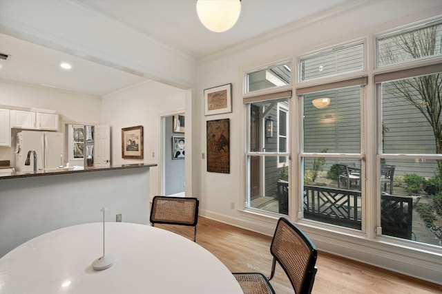 dining space featuring plenty of natural light, ornamental molding, and light wood-type flooring