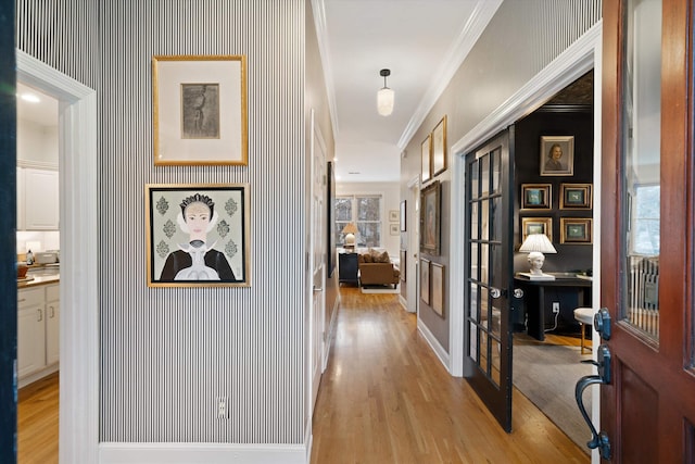 hallway with ornamental molding, french doors, and light wood-type flooring