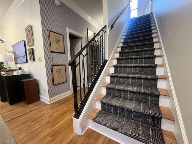 stairs with crown molding and wood-type flooring