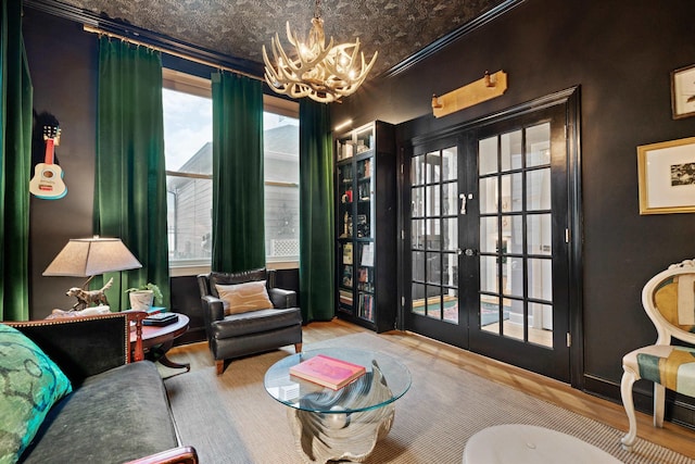 sitting room with ornamental molding, wood-type flooring, a chandelier, and french doors