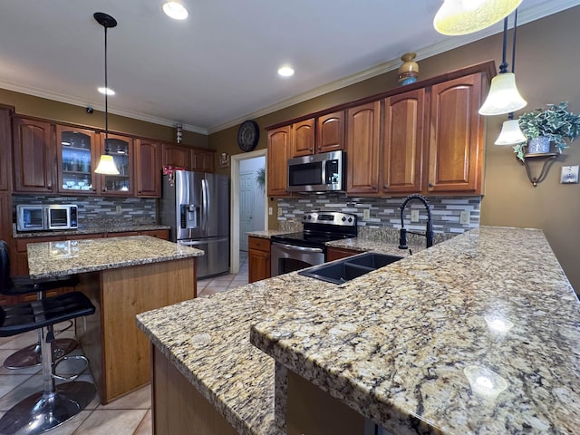 kitchen featuring pendant lighting, sink, crown molding, stainless steel appliances, and a kitchen island