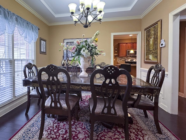 dining area with a tray ceiling, dark wood-type flooring, ornamental molding, and a chandelier