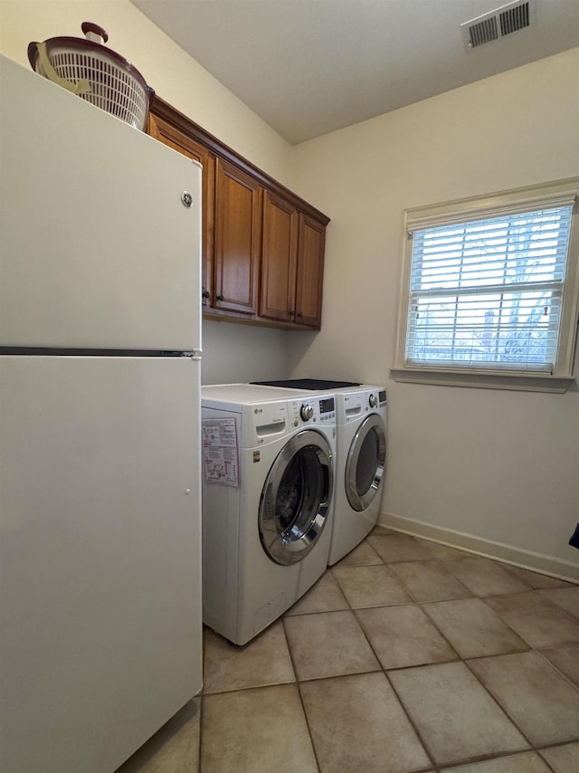 laundry area with cabinets, separate washer and dryer, and light tile patterned floors