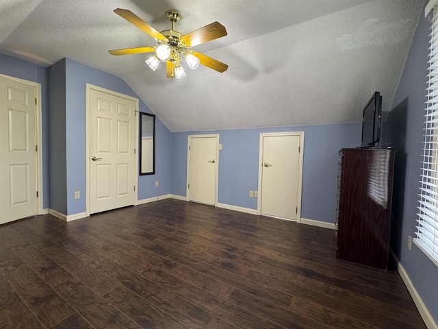 bonus room with ceiling fan, lofted ceiling, dark hardwood / wood-style floors, and a textured ceiling