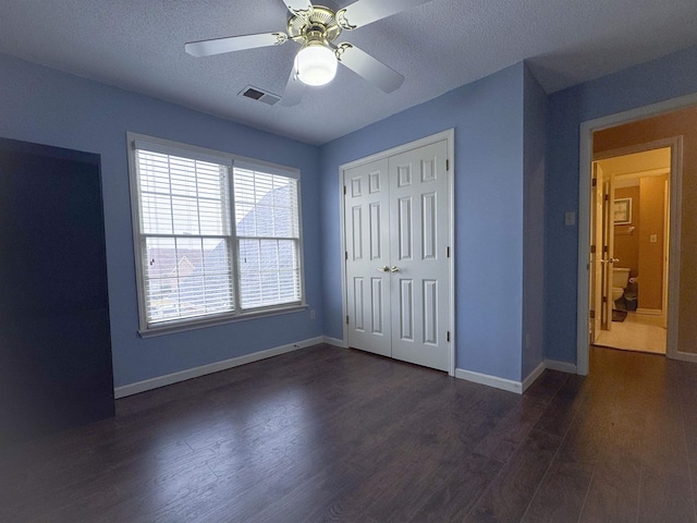 unfurnished bedroom featuring a closet, dark hardwood / wood-style floors, a textured ceiling, and ceiling fan