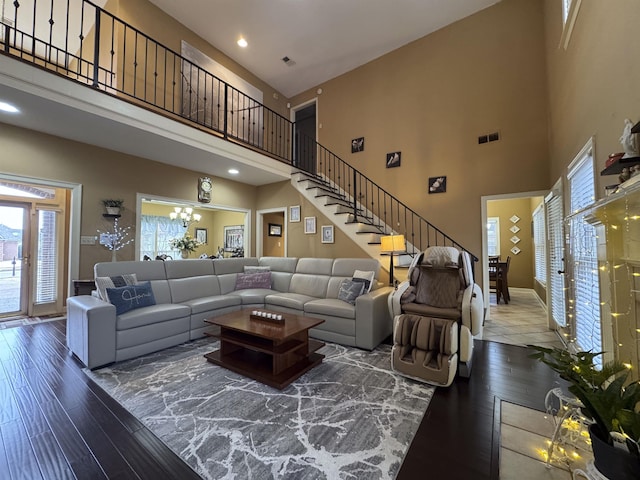 living room with dark hardwood / wood-style floors, a notable chandelier, and a towering ceiling