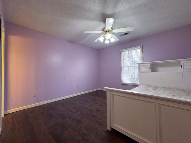 unfurnished bedroom with dark wood-type flooring, ceiling fan, and a textured ceiling