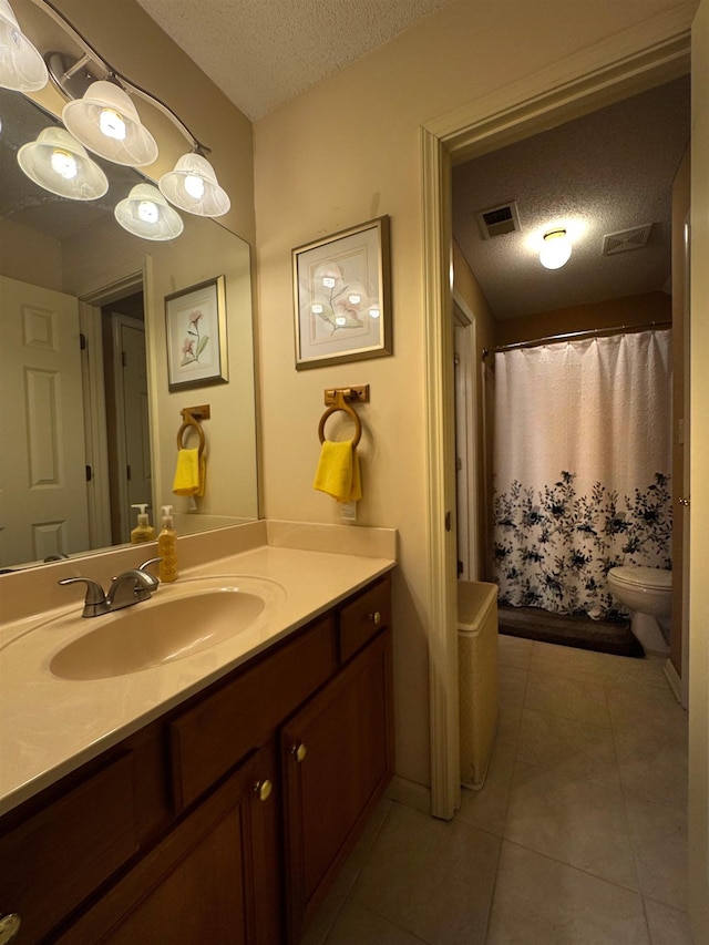 bathroom with tile patterned floors, toilet, a textured ceiling, and vanity