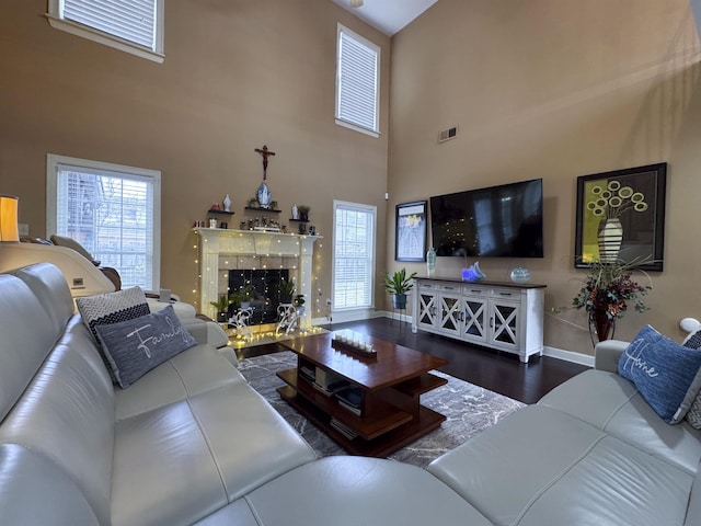 living room with a high ceiling, a premium fireplace, and dark wood-type flooring