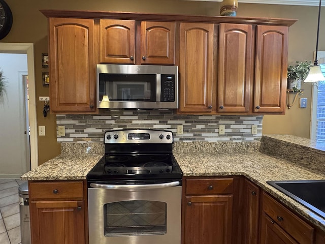 kitchen featuring light stone countertops, appliances with stainless steel finishes, light tile patterned flooring, and decorative light fixtures