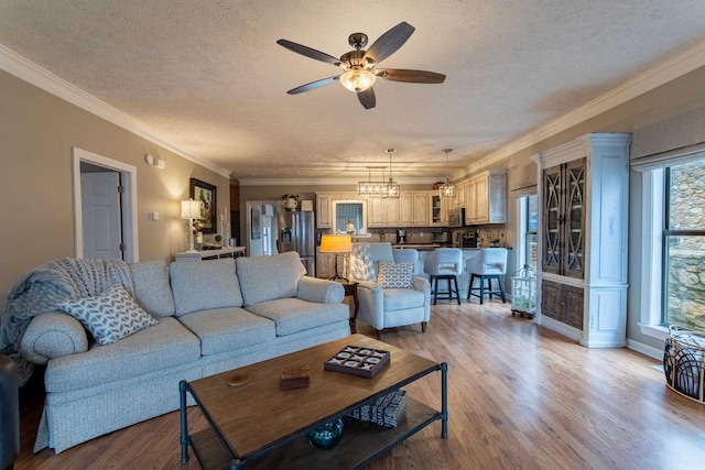 living room with crown molding, ceiling fan, a textured ceiling, and light hardwood / wood-style flooring