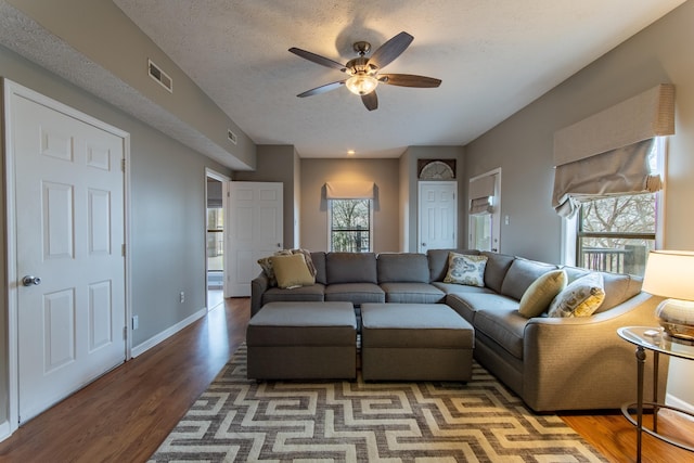 living room with hardwood / wood-style flooring, ceiling fan, and a textured ceiling