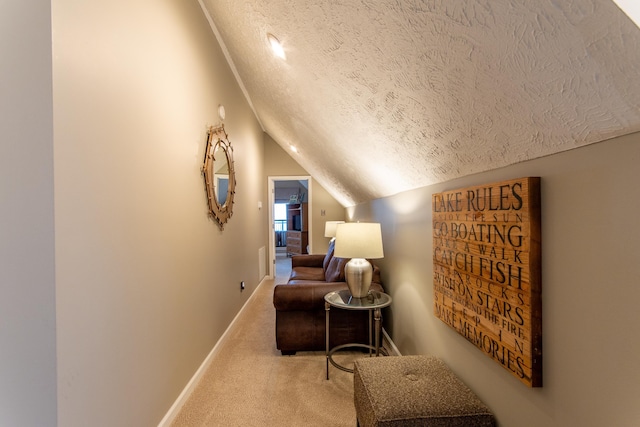 sitting room with lofted ceiling, carpet flooring, and a textured ceiling