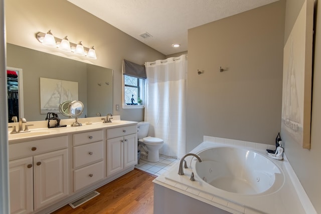 full bathroom featuring vanity, wood-type flooring, a textured ceiling, shower with separate bathtub, and toilet