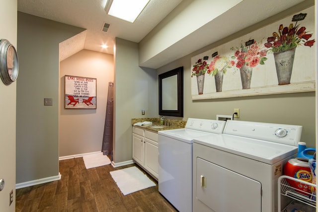 clothes washing area featuring cabinets, dark hardwood / wood-style flooring, and washer and clothes dryer