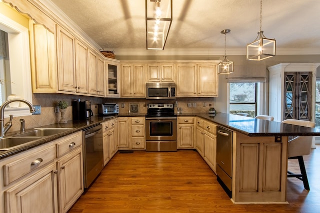 kitchen featuring appliances with stainless steel finishes, pendant lighting, sink, a breakfast bar area, and light hardwood / wood-style floors