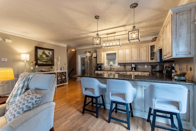 kitchen with decorative light fixtures, light hardwood / wood-style floors, kitchen peninsula, and appliances with stainless steel finishes