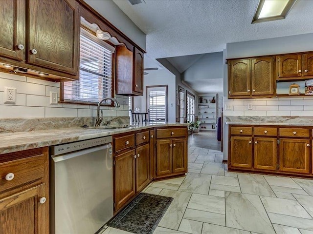 kitchen featuring tasteful backsplash, sink, stainless steel dishwasher, and a textured ceiling