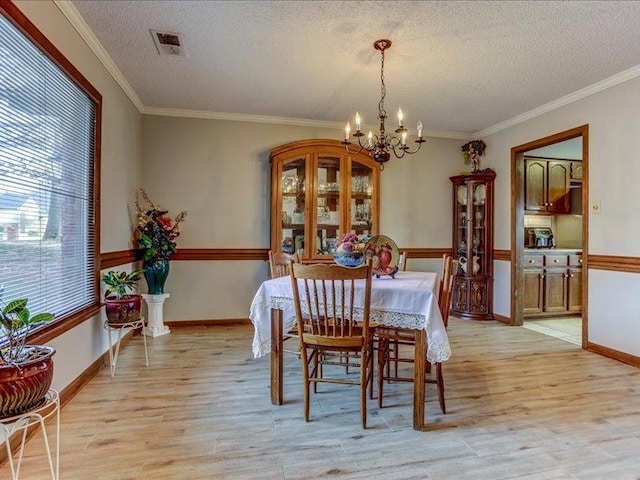 dining space featuring crown molding, a textured ceiling, and light wood-type flooring