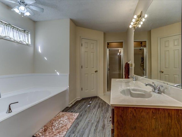 bathroom with separate shower and tub, a textured ceiling, vanity, ceiling fan, and hardwood / wood-style floors