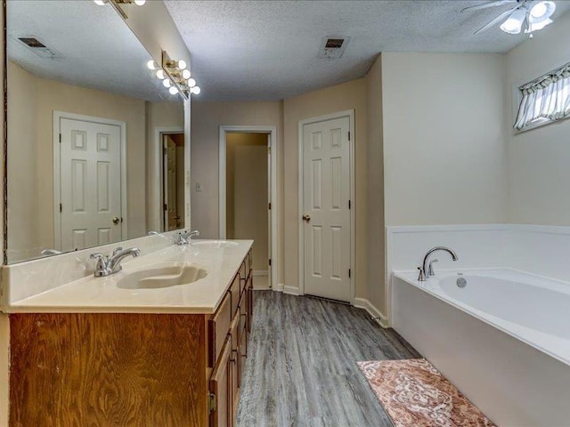 bathroom featuring hardwood / wood-style flooring, vanity, a textured ceiling, and a washtub