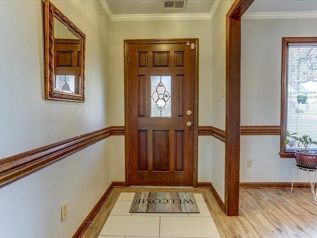 foyer entrance with crown molding, a textured ceiling, and light hardwood / wood-style flooring