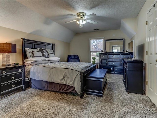 bedroom with ceiling fan, lofted ceiling, dark carpet, and a textured ceiling