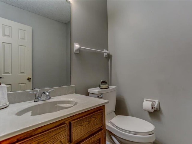 bathroom with vanity, a textured ceiling, and toilet