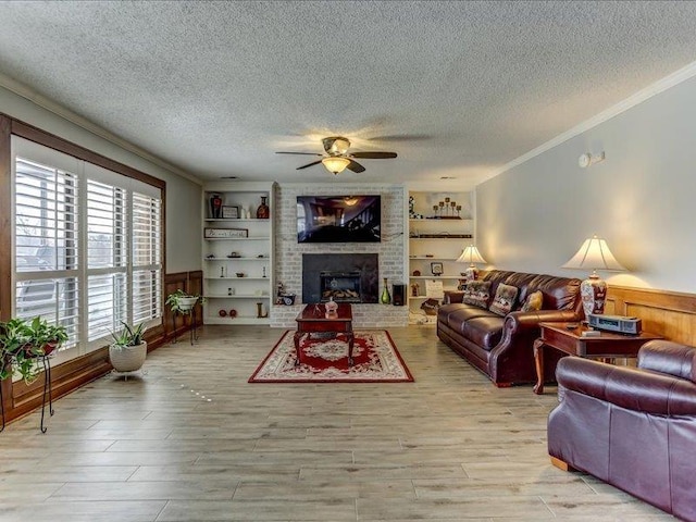 living room with ornamental molding, light hardwood / wood-style flooring, built in features, and a textured ceiling