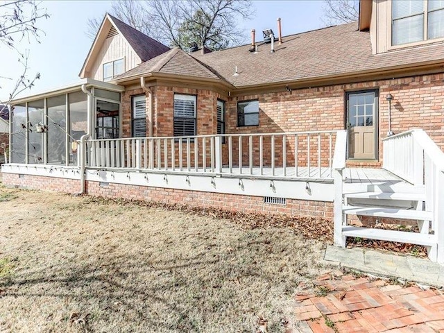 back of property featuring a sunroom and a lawn