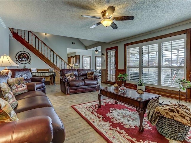 living room featuring vaulted ceiling, ceiling fan, a textured ceiling, and light hardwood / wood-style floors