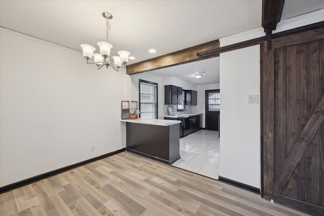 kitchen with a notable chandelier, pendant lighting, light hardwood / wood-style floors, a barn door, and kitchen peninsula