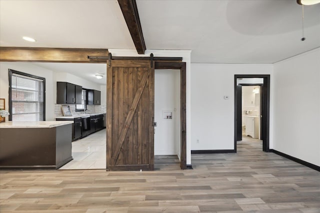 kitchen with beam ceiling, tasteful backsplash, light hardwood / wood-style floors, and a barn door